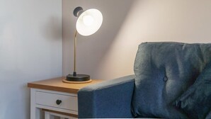 A bedside table with a lamp, a drawer, and a blue upholstered chair. - Modern & Spacious 1 Bed Apartment in Manchester (Salford)