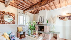 A cozy living room with a fireplace, a wooden ceiling, and a large mirror.