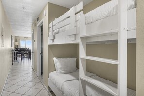 A room with bunk beds, a dining area with chairs, and a view of the outdoors.