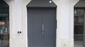 Eine moderne Gebäudefassade mit einer großen, dunkelgrauen Tür, einem kleinen Fenster darüber und der deutlich sichtbaren Nummer "178" an der Wand.