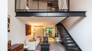 A modern living room with a sofa, coffee table, and a staircase leading to an upper level.