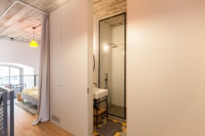 A modern bathroom with a shower, a sink, and a wooden floor.
