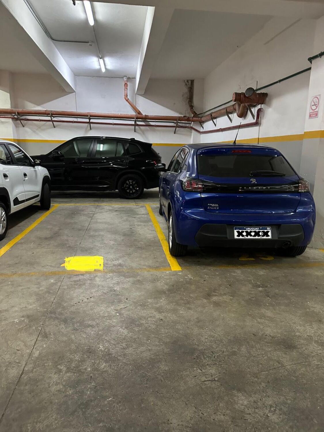 A parking garage with three cars parked in designated spaces.