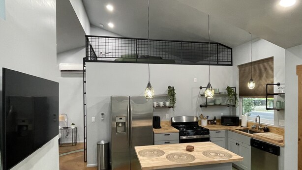 A modern kitchen with a central island, stainless steel appliances, and pendant lighting.