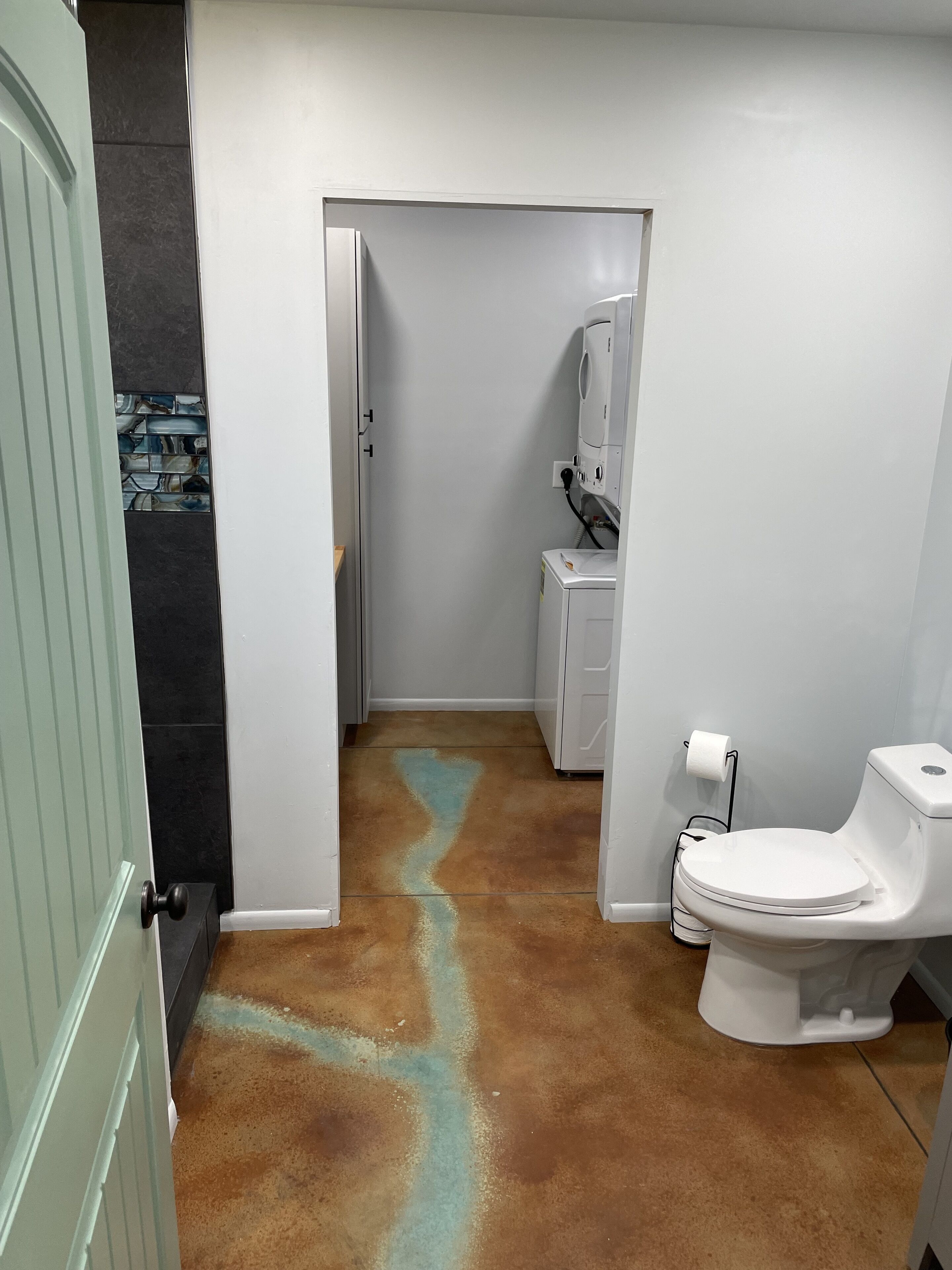 Une salle de bain avec des toilettes blanches, un porte-serviettes et un espace douche.