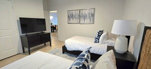 A hotel room with two beds, a TV, a desk, and a lamp.