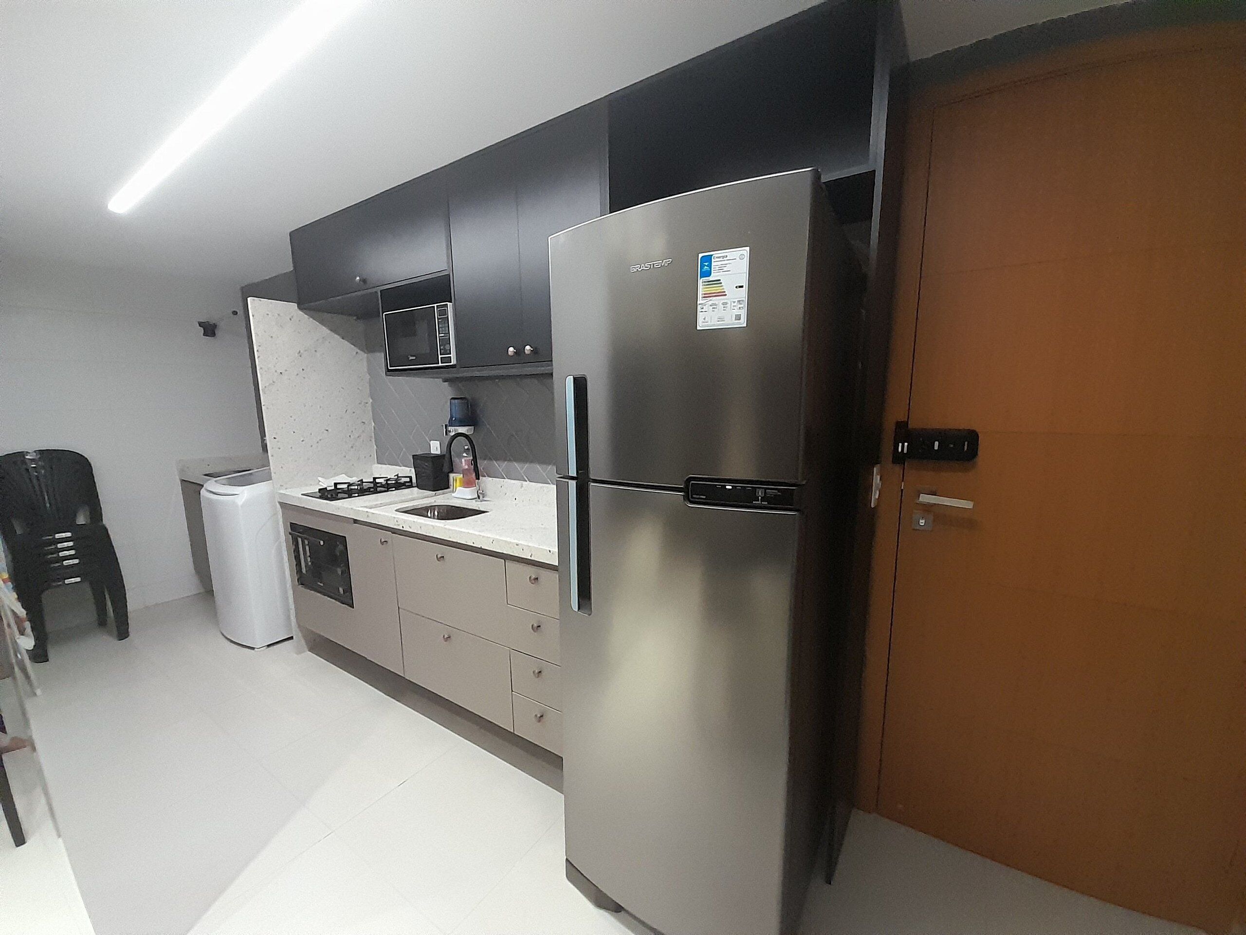 A kitchen with a refrigerator, microwave, sink, and cabinets.