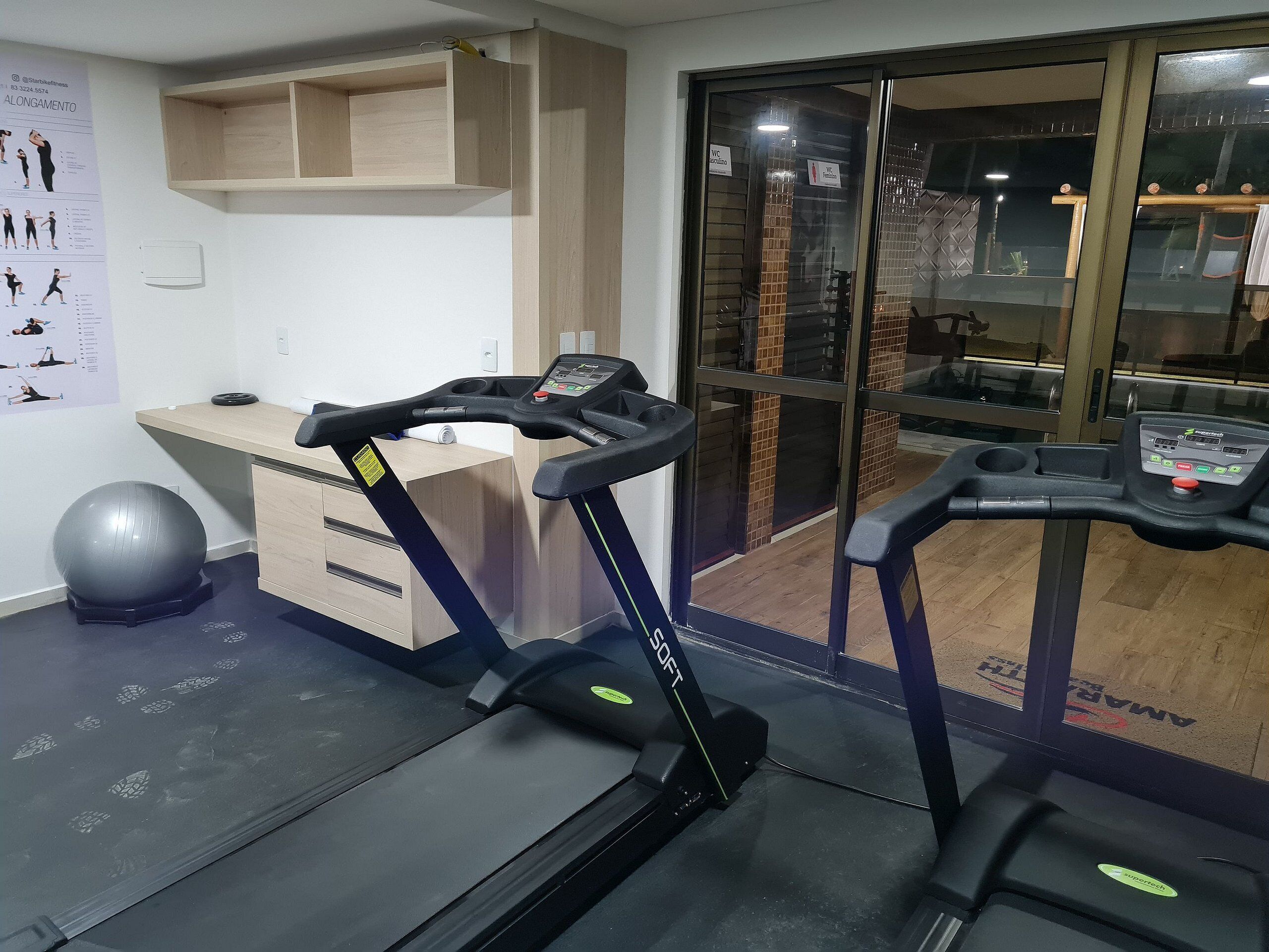 Un gimnasio con cintas de correr, una bicicleta estática y un balón de fitness.