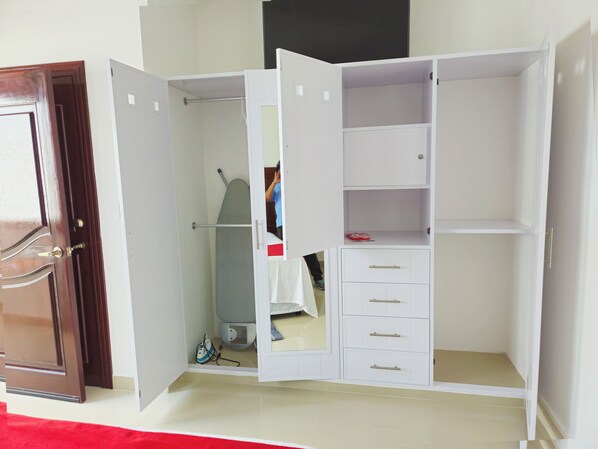 Un vestidor con puertas abiertas, una barra para colgar ropa y algunos cajones.