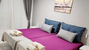 A neatly made bed with a purple bedspread and two pillows, a bedside table, and a wall-mounted artwork. - El Mirador Los Cristianos, 20 sqm terrace and incredible 40 sqm roof terrace (CN)