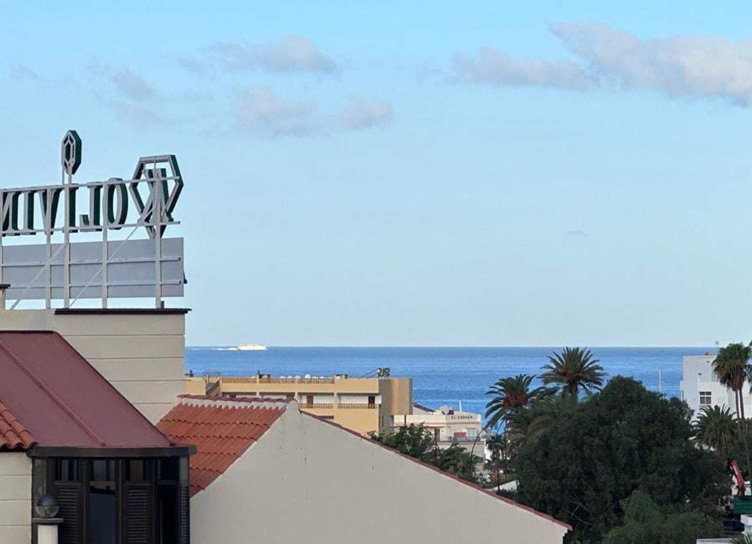Vistes costaneres amb un edifici que té un rètol al terrat i una vista clara del mar.