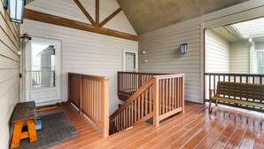 Eine Holzterrasse mit einer Bank, einer Treppe und einer Tür mit Fensterteil.