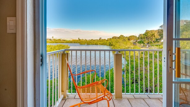 A balcony with a view of a river and greenery.