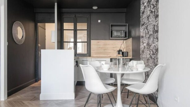 A modern kitchen with a microwave, a coffee machine, and a wooden countertop. There is a dining area with a white table and chairs. - The Parrot 🦜 from La Rochelle 🐝 (La Rochelle)