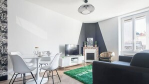 A modern living room with a dining area, a fireplace, and a large window. - The Parrot 🦜 from La Rochelle 🐝 (La Rochelle)