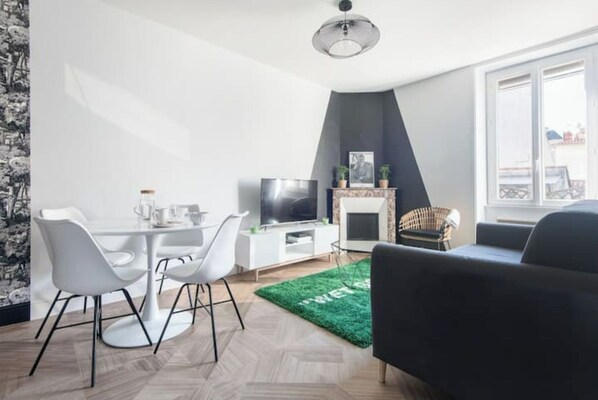 Un salon moderne comprenant un coin repas, une cheminée et une grande fenêtre.