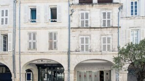 A building with two storefronts, one with a sign reading "Les Perot-Quais" and another with "Jean." - The Parrot 🦜 from La Rochelle 🐝 (La Rochelle)