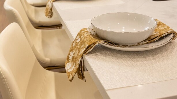 A modern kitchen with a long countertop, a patterned backsplash, and a sink.