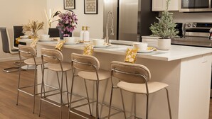 A modern kitchen with a central island, bar stools, stainless steel appliances, and a minimalist design.