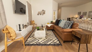 A modern living room with a brown leather sofa, a white coffee table, and a patterned rug.