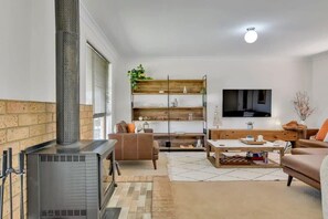 A modern living room with a fireplace, a television, and a bookshelf.