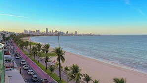 A coastal cityscape with a beach, palm trees, and a road with parked cars. - Manaíra Palace Residence (João Pessoa)