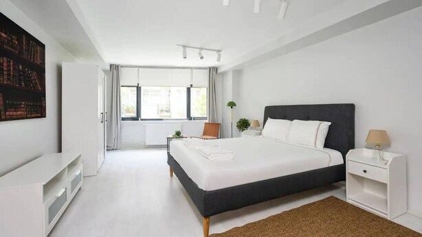 Ein modernes Schlafzimmer mit einem großen Bett, Nachttischen, einem Schreibtisch und einem Bücherregal.