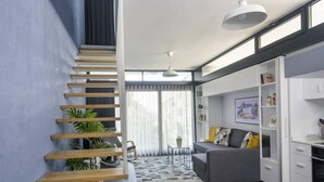 Een modern interieur met een houten trap, een grijze bank en een eethoek.
