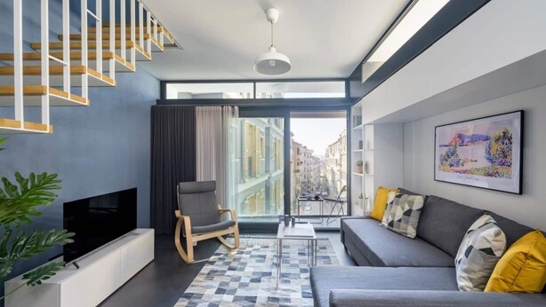 Een moderne woonkamer met een bank, een stoel, een televisie en een trap.