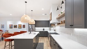 Una cocina moderna con una isla central, armarios grises y encimera blanca.