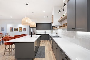 A modern kitchen with a central island, grey cabinets, and a white countertop.