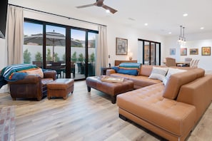 A spacious living room with leather sofas, a coffee table, and a dining area with a table and chairs.