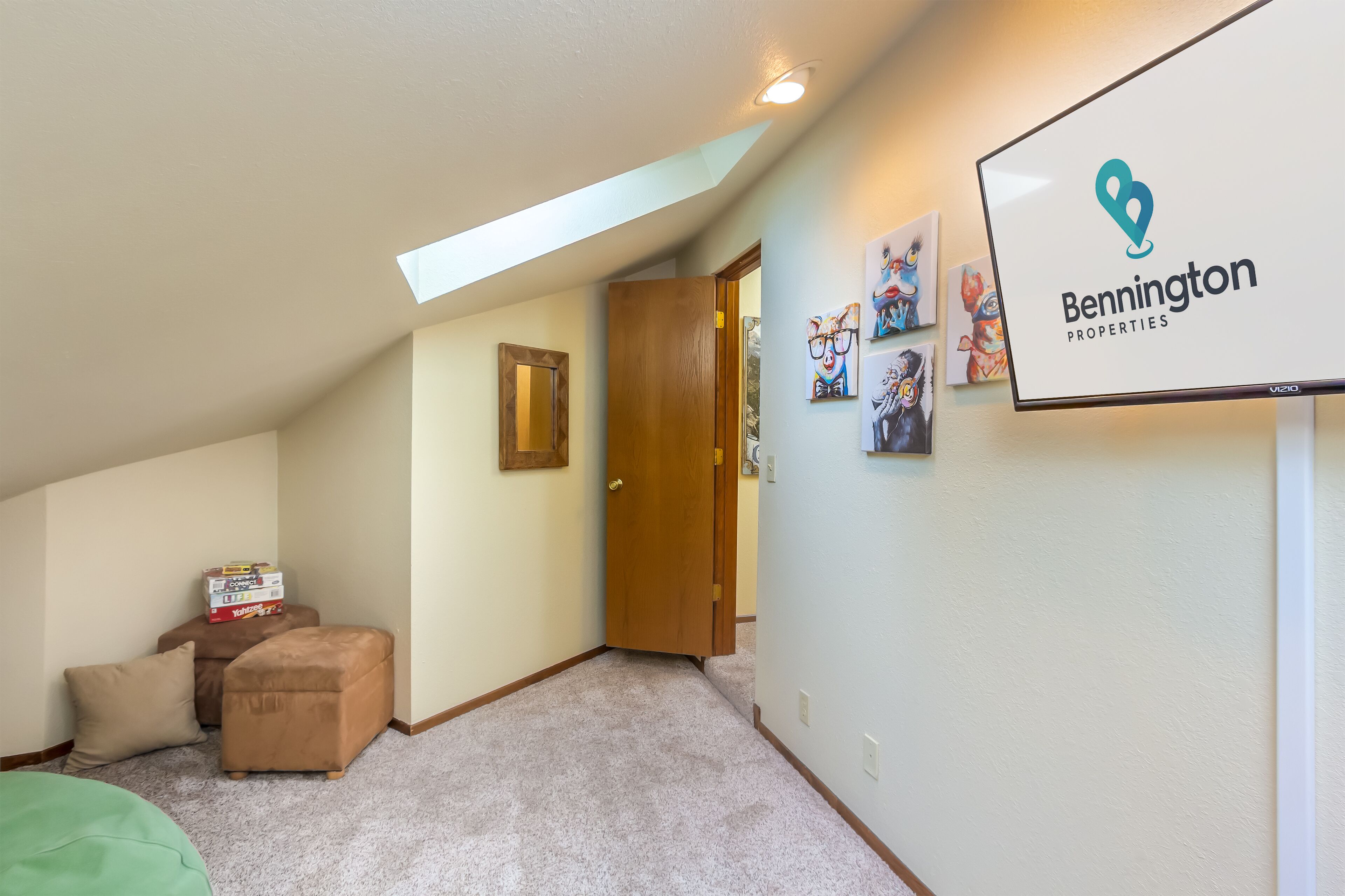 A hallway with a carpeted floor, a wooden door, and a Bennington Properties sign.