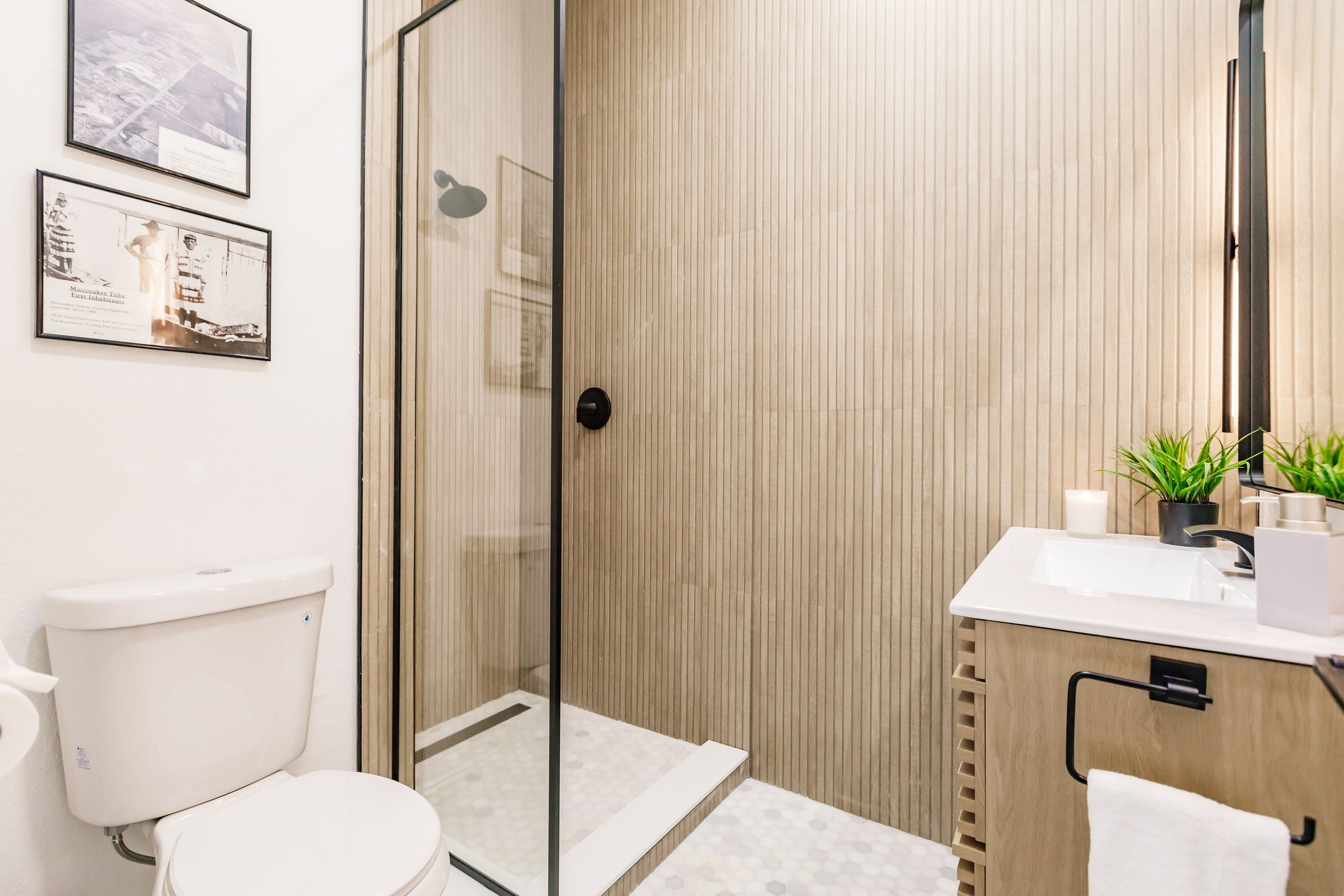 Een moderne badkamer met een douchecabine van glas, een wit toilet en een wastafel met spiegel.
