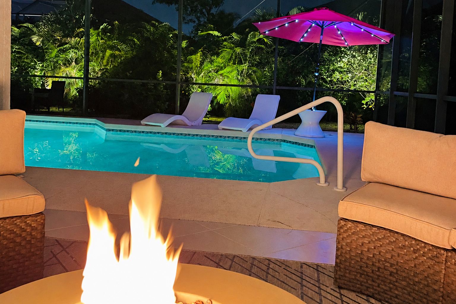 Une piscine avec des chaises longues et un foyer extérieur.