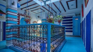 Una habitación con una decoración azul y blanca, un ventilador de techo decorativo y un suelo estampado.