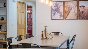 A dining area with a table, chairs, a hanging light fixture, and framed artwork on the wall. - Amazing Family Retreat w/ Fenced Yard & BBQ! (Stevens Point)