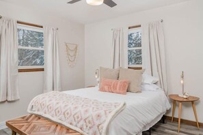 A bedroom with a bed, two windows, a bedside table, a bench, and a ceiling fan. - Amazing Family Retreat w/ Fenced Yard & BBQ! (Stevens Point)