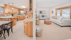 A modern kitchen with wooden cabinets and a dining area, a living room with a sofa and a coffee table, and large windows with a view of a snowy landscape. - Amazing Family Retreat w/ Fenced Yard & BBQ! (Stevens Point)