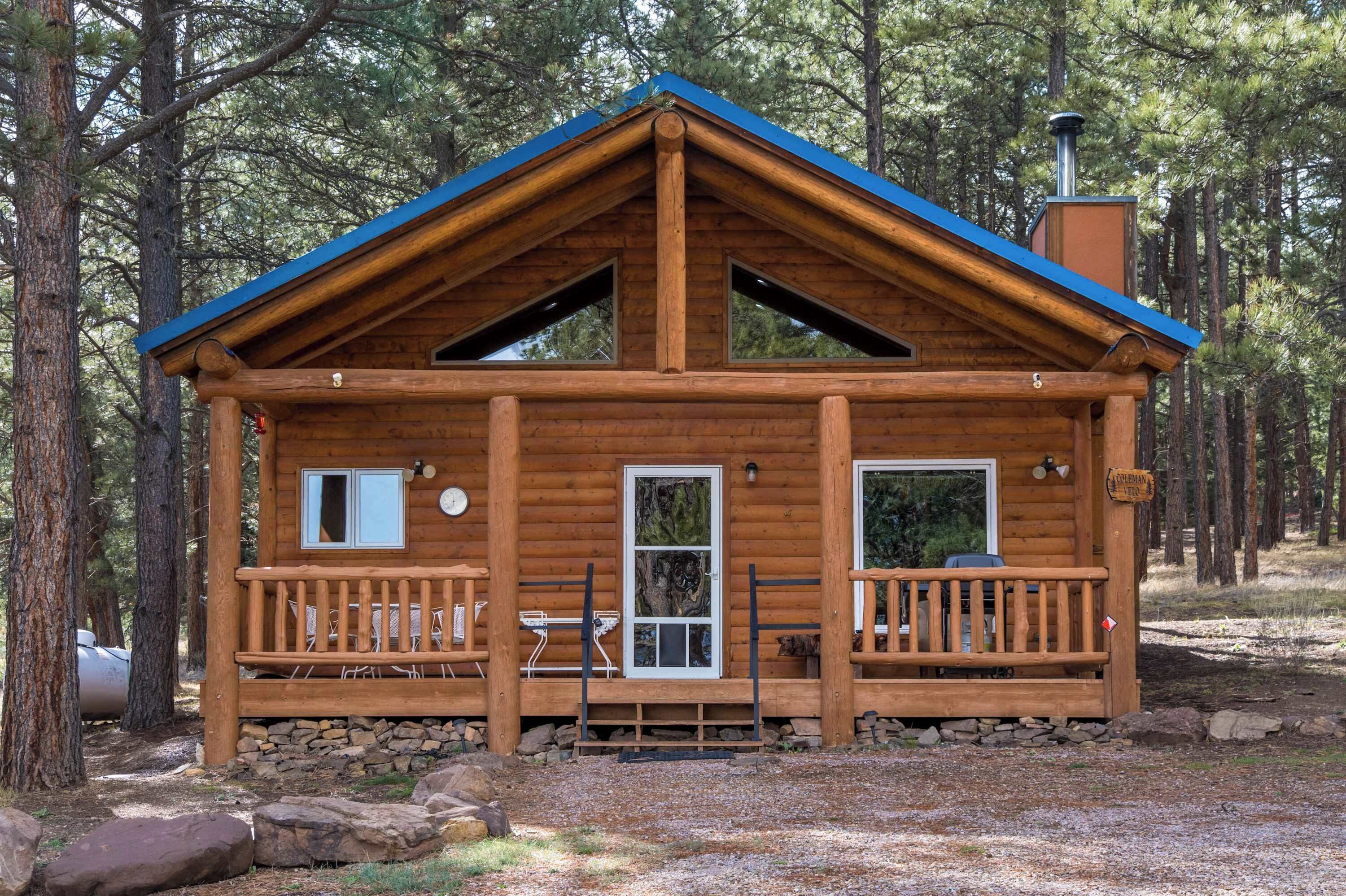 Eine Holzhütte mit blauem Dach, zwei Fenstern, einer Tür und einer Veranda.