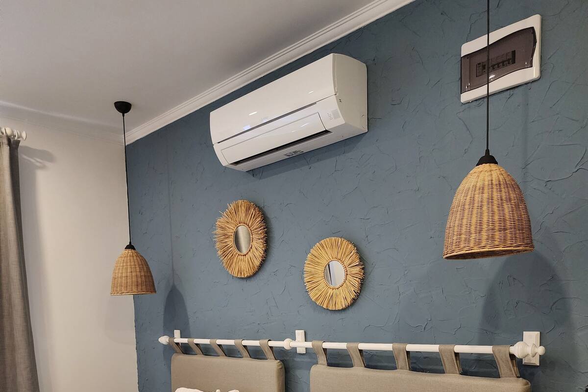 Een hotelkamer met twee bedden, een grote airconditioner, decoratieve spiegels aan de muur en een hangende吊灯.