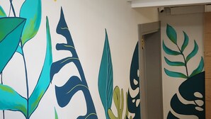 Ein Zimmer mit einer weißen Wand und großen, farbenfrohen abstrakten Pflanzenmotiven.