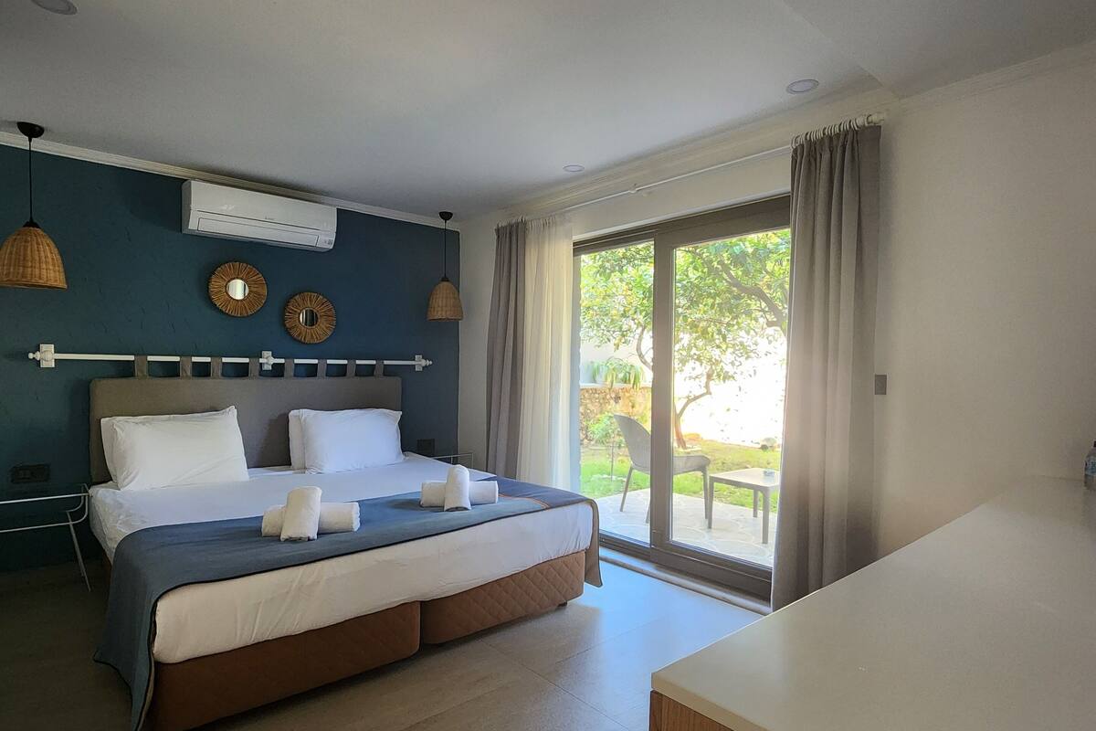 Een moderne hotelkamer met een groot bed, een nachtkastje, een raam met gordijnen en een airconditioner aan de muur.