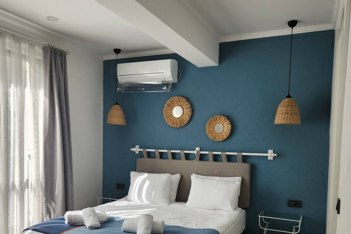 Een moderne slaapkamer met een groot bed, een plafondventilator en een wandairconditioner.