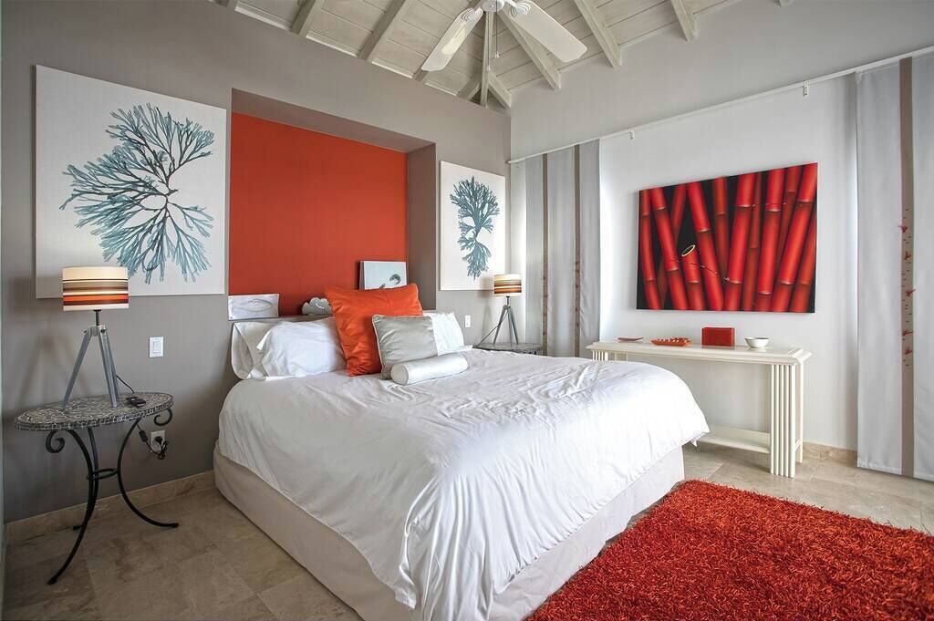 A modern bedroom with a large bed, a white bedside table, and a red rug.