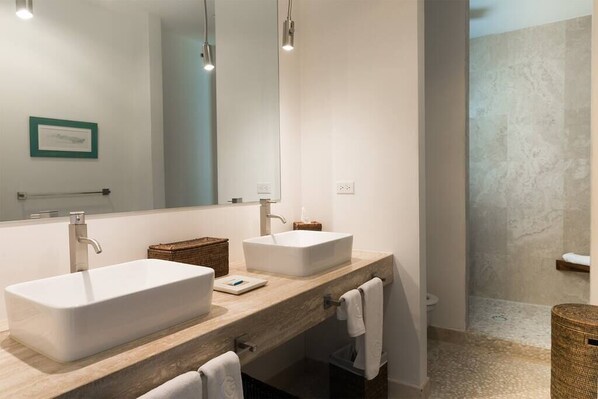 A modern bathroom with two sinks, a large mirror, and a shower area.