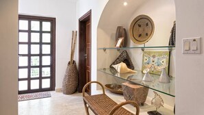 Un pasillo con una vitrina de vidrio que contiene objetos decorativos, una cesta tejida y una puerta que da a otra habitación.