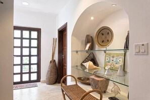 A hallway with a glass display case containing decorative items, a woven basket, and a door leading to another room.