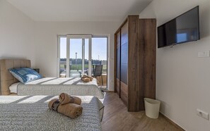 A modern bedroom with two beds, a TV, and a view of a sports field. - Villa Maristra-2 -  Sea view - beach - istriensonne 0723 (Medulin)