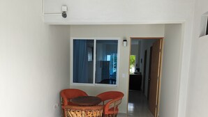 Una piccola zona pranzo con un tavolo rotondo e due sedie, una finestra con tende e vista sull'esterno.